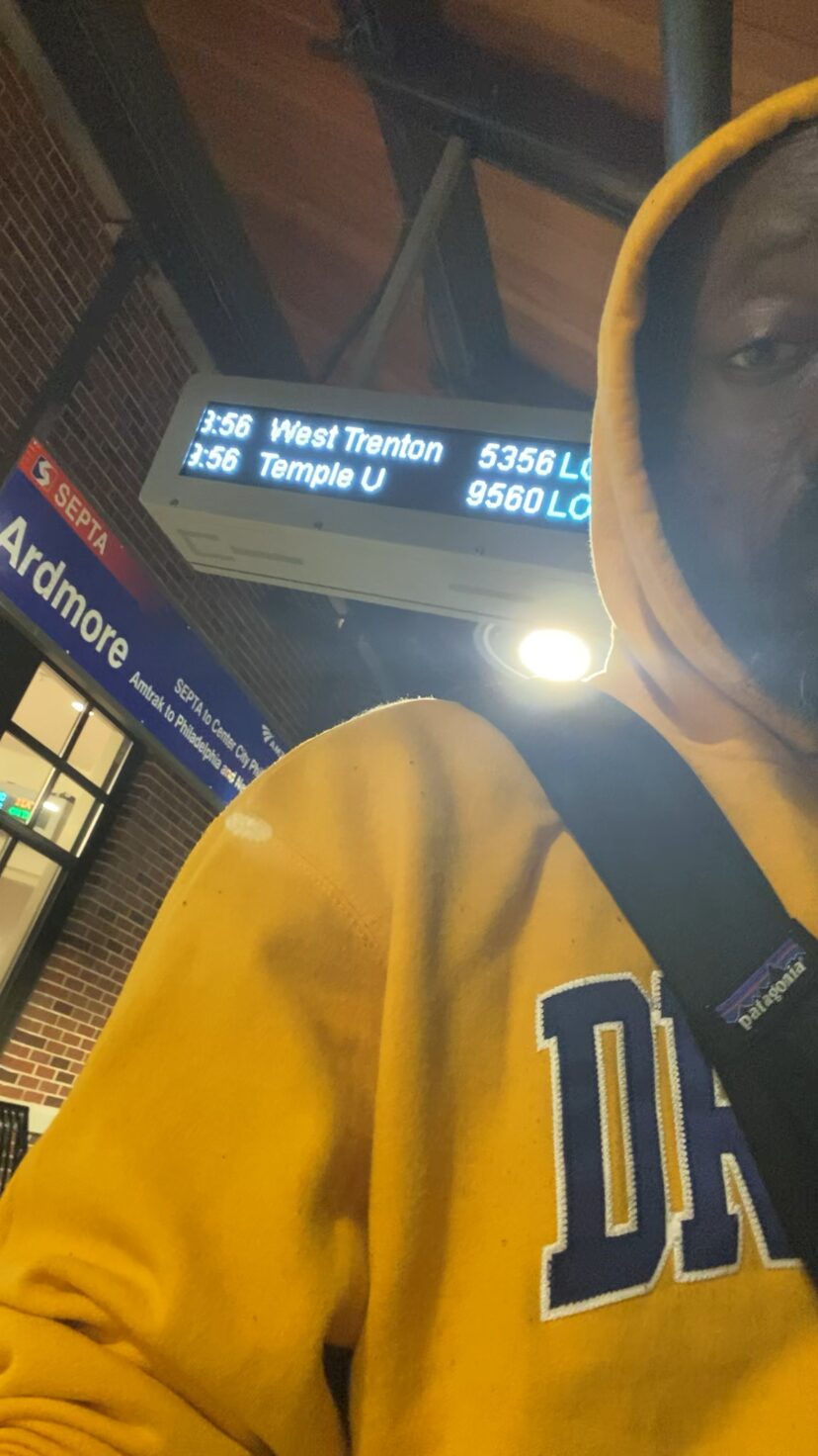 A selfie at night on the train platform, gold Drexel hoodie, the departures board overhead.